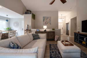 Living area with a ceiling fan, wood finished floors, a chandelier, and a towering ceiling