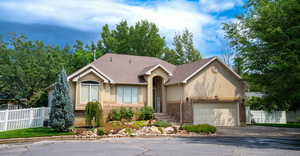 Single story home with stucco siding, roof with shingles, a garage, and driveway