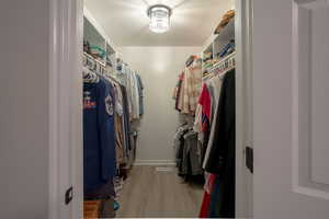 Walk in closet with light wood-style flooring