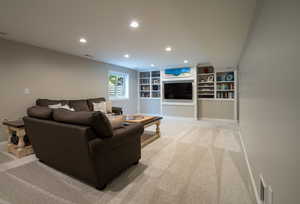Living room with light carpet, recessed lighting, and built in shelves