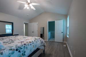 Bedroom with wood finished floors, vaulted ceiling, ensuite bath, ceiling fan, and multiple windows