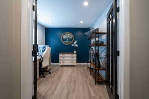 Home office with light wood-style floors and recessed lighting