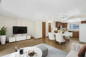 Living area featuring a ceiling fan and light tile patterned floors *Virtually Staged*