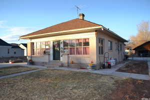 Bungalow-style home featuring a chimney, stucco siding, and entry steps
