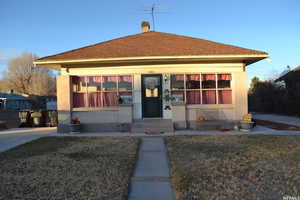 View of front of house featuring a front yard, a chimney, roof with shingles, and stucco siding