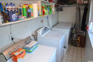 Laundry room with washer and clothes dryer and light flooring
