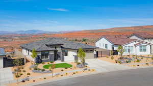 View of front facade featuring stone siding, driveway, stucco siding, a mountain view, and a garage
