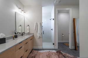 Bathroom with vanity, a shower stall, and dark tile patterned floors
