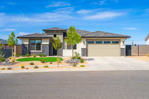 Prairie-style house with stucco siding, driveway, stone siding, and an attached garage