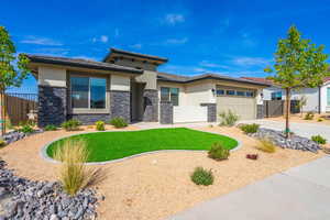 Prairie-style house with stone siding, stucco siding, an attached garage, and concrete driveway
