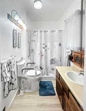 Full bathroom featuring a shower stall, light wood-style floors, and vanity