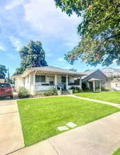 View of front of property with a porch, a front lawn, a shingled roof, and driveway