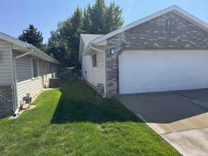 View of side of home featuring concrete driveway and a yard