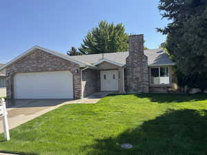 Ranch-style house featuring a front yard, a shingled roof, an attached garage, concrete driveway, and brick siding