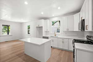 Kitchen featuring appliances with stainless steel finishes, white cabinets, a kitchen island, and recessed lighting