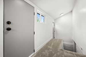 Corridor featuring carpet floors and vaulted ceiling