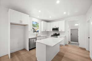 Kitchen featuring white cabinets, a center island, appliances with stainless steel finishes, light wood-style floors, and recessed lighting