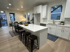 Kitchen featuring white cabinets, light wood-style floors, a breakfast bar area, a kitchen island, and recessed lighting
