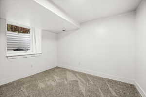 Carpeted spare room featuring baseboards