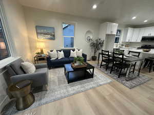 Living area with light wood finished floors and recessed lighting