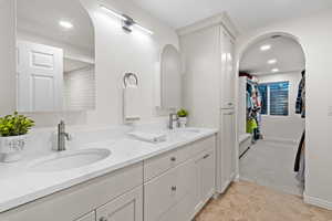 Full bathroom featuring double vanity, light tile patterned floors, a spacious closet, and recessed lighting