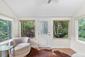 Living area with lofted ceiling, wood finished floors, healthy amount of natural light, and ceiling fan