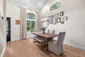 Dining room featuring high vaulted ceiling, light wood finished floors, a chandelier, and recessed lighting