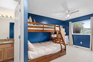 Bedroom featuring light carpet, a ceiling fan, a textured ceiling, and ensuite bathroom