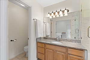 Ensuite bathroom with light tile patterned flooring, a stall shower, and vanity