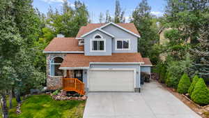 View of front facade with roof with shingles, driveway, stone siding, and a chimney