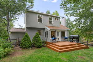 Back of property with stucco siding, a chimney, a wooden deck, and roof with shingles