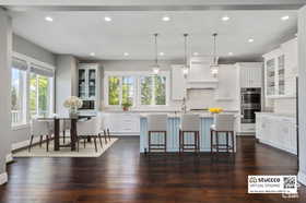 Kitchen with glass insert cabinets, plenty of natural light, decorative light fixtures, a breakfast bar, and recessed lighting