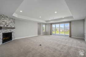Unfurnished living room with a raised ceiling, a fireplace, carpet floors, and recessed lighting