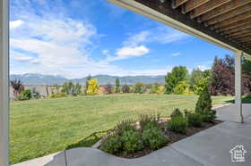 View of green lawn with a mountain view and a patio area