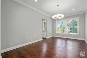 Unfurnished room featuring ornamental molding, dark wood-style floors, a chandelier, and recessed lighting