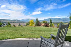 View of green lawn with a mountain view and a patio