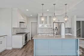 Kitchen featuring white cabinets, appliances with stainless steel finishes, glass insert cabinets, and recessed lighting