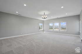 Empty room with carpet, recessed lighting, and a chandelier