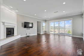 Unfurnished living room with a premium fireplace, ornamental molding, dark wood-style flooring, and recessed lighting