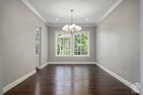 Unfurnished dining area with crown molding, a chandelier, dark wood finished floors, and recessed lighting