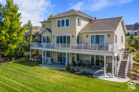 Rear view of house with a patio area, a wooden deck, a lawn, and stairway
