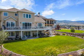 Back of house with a yard, a patio area, a deck with mountain view, and stairs