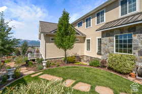 Rear view of house featuring a standing seam roof, a yard, stone siding, and a metal roof