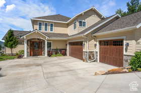 View of front facade featuring driveway, stone siding, and a garage
