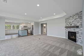 Unfurnished living room with a fireplace, dark colored carpet, recessed lighting, and a raised ceiling