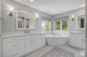 Bathroom featuring a freestanding tub, two vanities, and recessed lighting