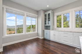 Bar featuring glass insert cabinets, dark wood-style floors, recessed lighting, white cabinets, and light stone countertops