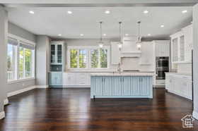 Kitchen featuring glass insert cabinets, plenty of natural light, pendant lighting, light countertops, and recessed lighting