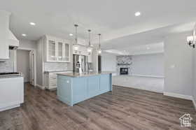 Kitchen featuring white cabinetry, open floor plan, glass insert cabinets, a fireplace, and decorative light fixtures