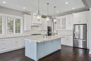 Main level kitchen with stainless steel appliances, light countertops, white cabinets, accent paint
